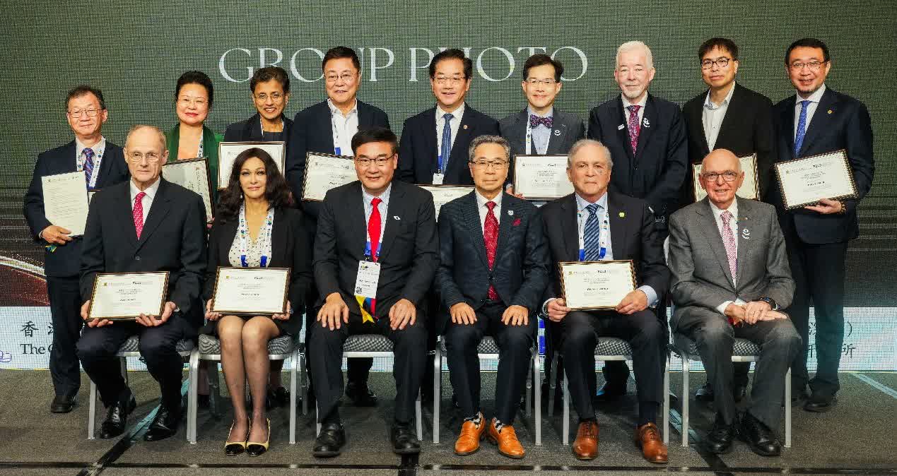 Group photograph of international experts at a PIERI symposium, with several seated honorees holding Honorary Professor certificates.
